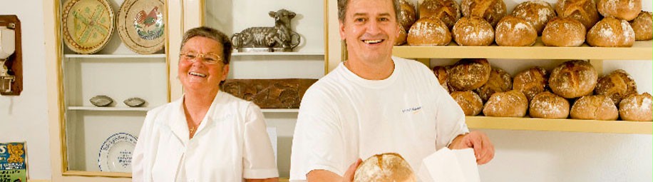Das Bild zeigt eine Frau und einen Mann beim Brotverkauf.
