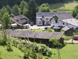 Das Bild zeigt das Fachwerkgebäude der Gammersbacher Mühle mit den dazugehörigen Hofanlagen von einer Anhöhe aus.